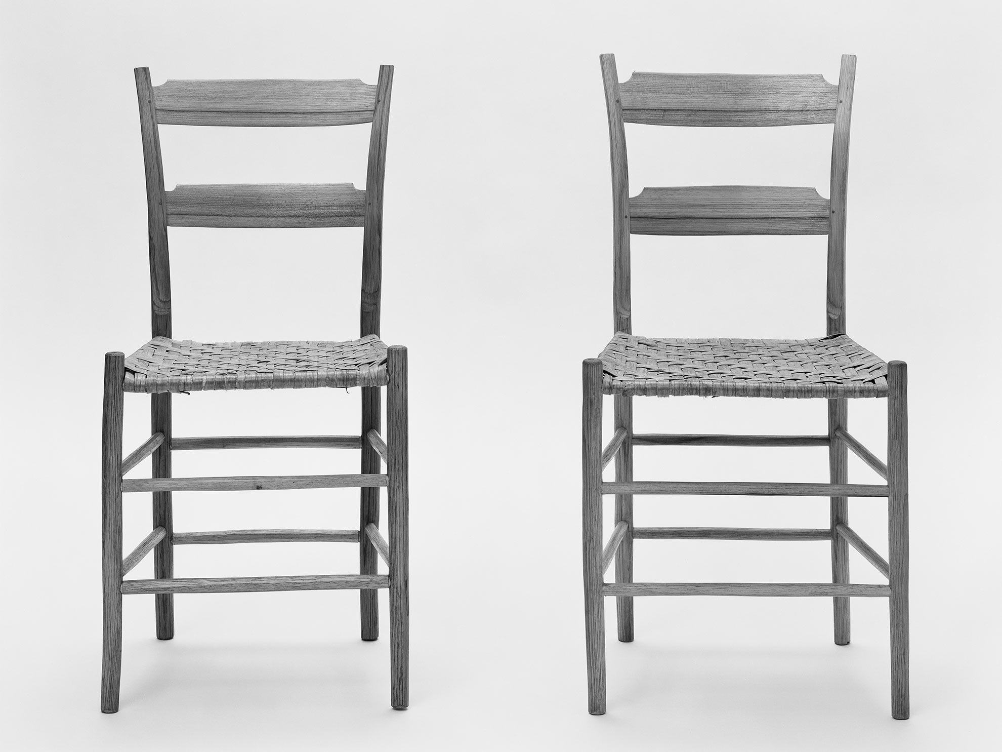 Two slim wooden chairs stand side by side