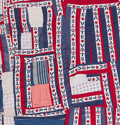 Detail image of a red, white, and blue quilt with contrasting strips and blocks of fabric.