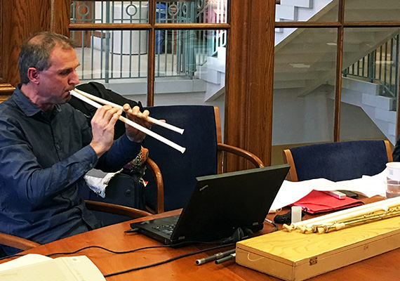 Music archaeologist playing preliminary 3D-printed replica of a pair of wooden pipes