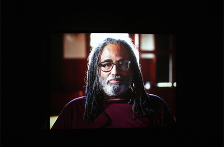 A man with glasses and grey hair stares directly a head.