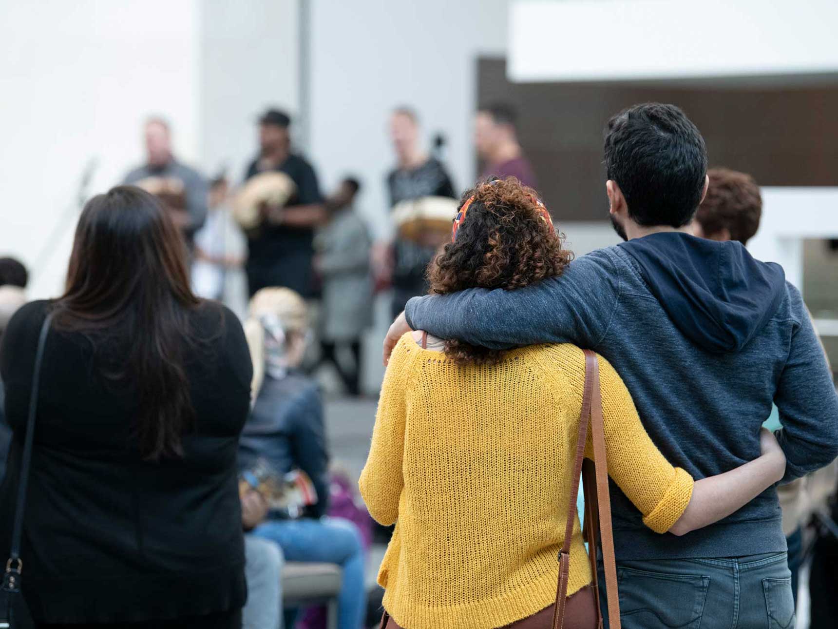 Couple in side-by-side embrace watching performance in Shapiro Family Courtyard