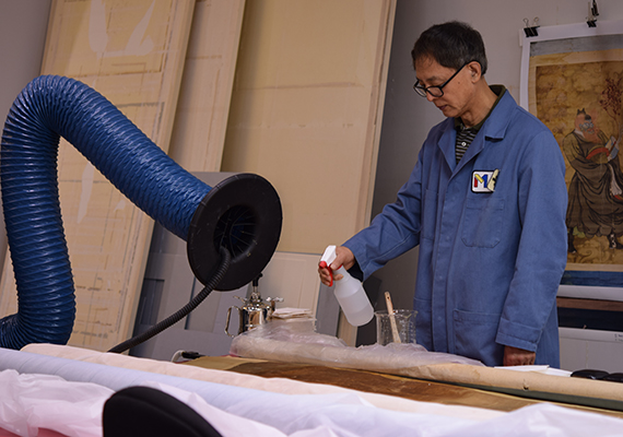 Conservator sprays the painting with an isopropyl alcohol solution