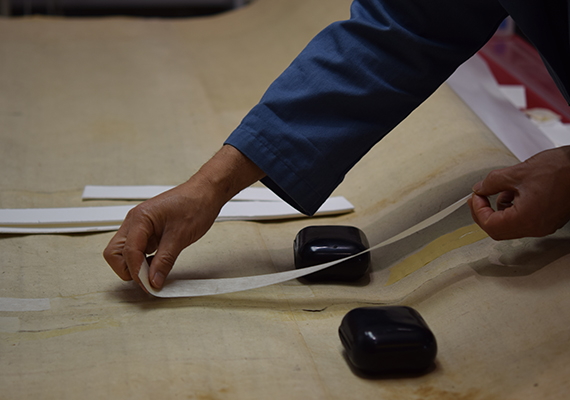 Conservator applies bast paper strips to the painting