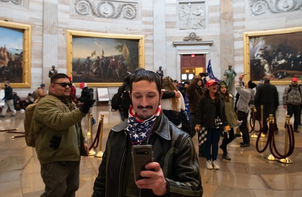 Rioters stand before John Trumbull's paintings of scenes from American history in the Capitol Rotunda on Wednesday, January 6, 2021.