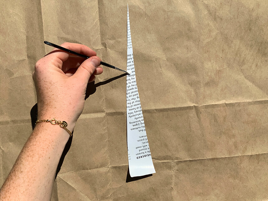 using brush to apply glue to top pointed tip of one triangular cut-out