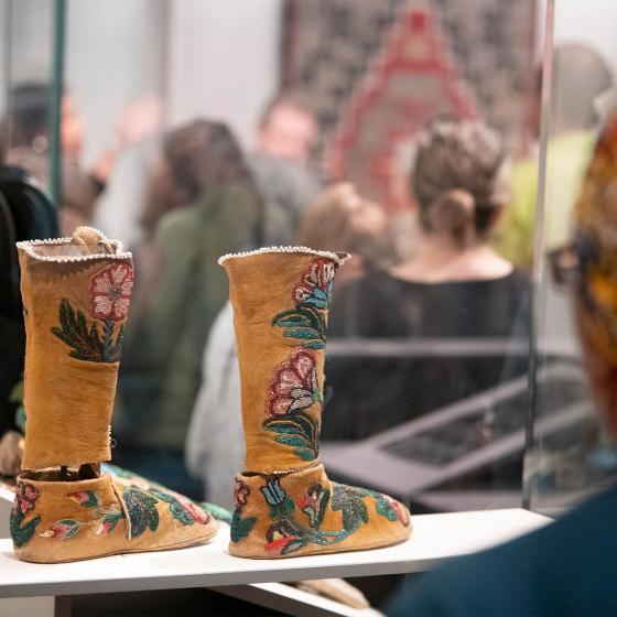 visitor looking at pair of moccasin boots in glass case
