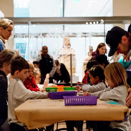 A group of kids sit around a table and make art. 