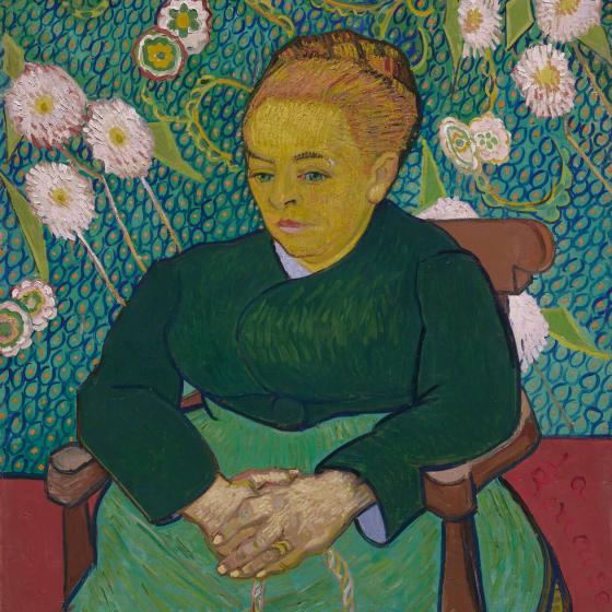 Vincent van Gogh painting featuring woman in green dress and hair in a bun, sitting on chair in front of green wall covered in white flowers