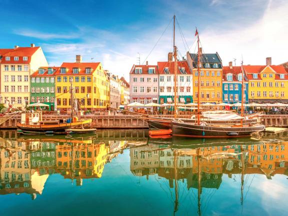 Row of colorful buildings in Stockholm adjacent to water where a tall ship is anchored