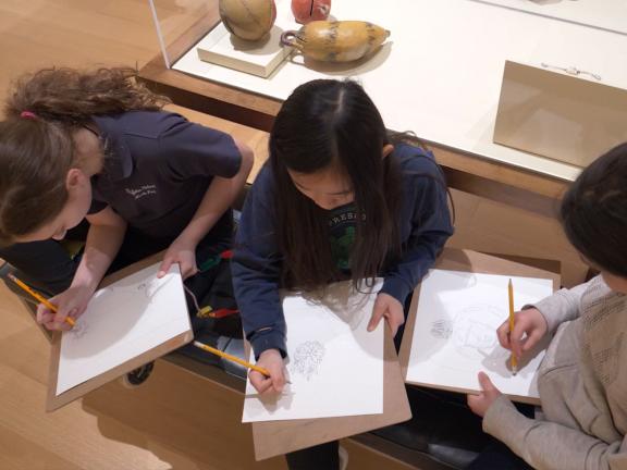 Students sketching on bench in Native North American Art gallery