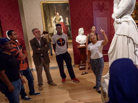 Group of students with teacher looking up at sculpture in Salon gallery