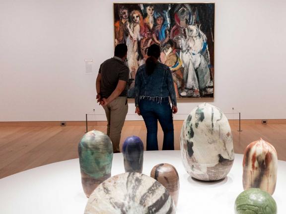 couple looking at a painting with ceramic pots in the foreground