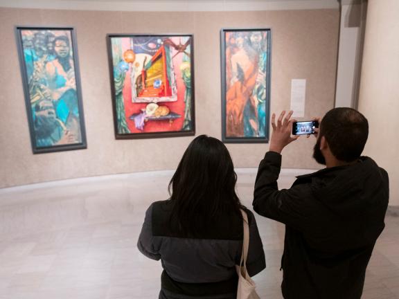 Two visitors looking at three paintings hanging in rotunda gallery