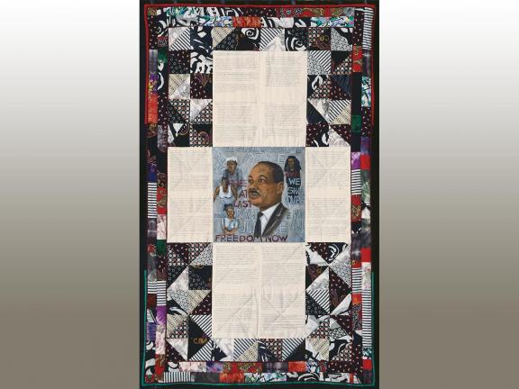 Photograph of a quilt with an image of Martin Luther King, portions of text and other people.