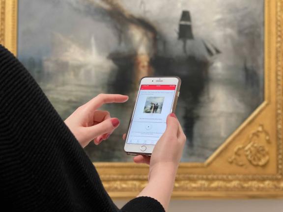 Close-up of smartphone screen with MFA Mobile app displayed; Turner painting in background