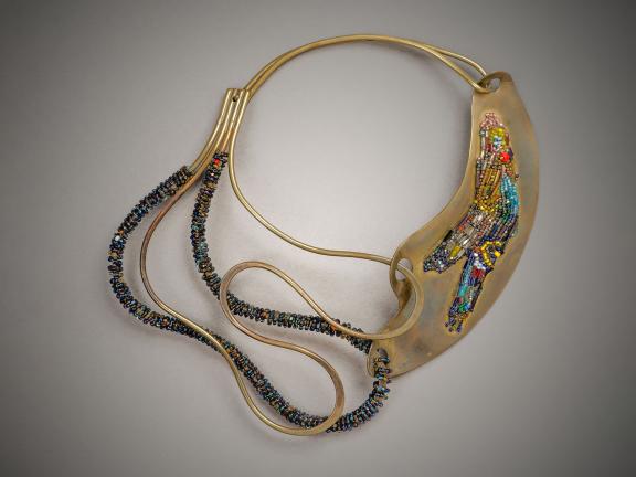 A photo of an ornate necklace made from brass, glass beads, and leather.