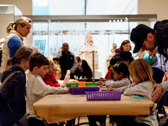 A group of kids sit around a table and make art.