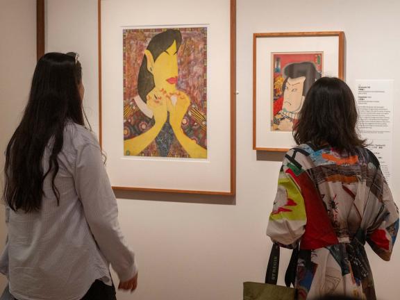 Two visitors observe a traditional Japanese print next to a more modern Japanese print 