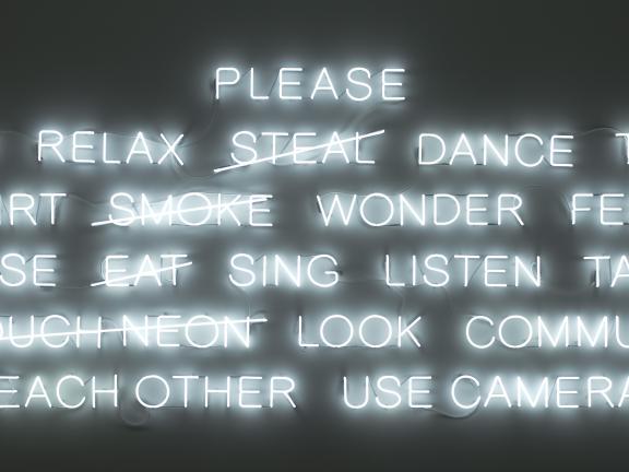 Detail of neon artwork made up of six lines of capital letters spelling out words such as “relax,” “wonder,” “sing,” and “look”
