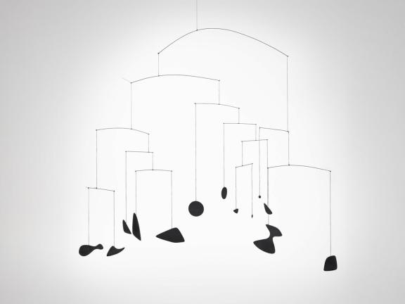 A black mobile of abstract shapes against a white backdrop.