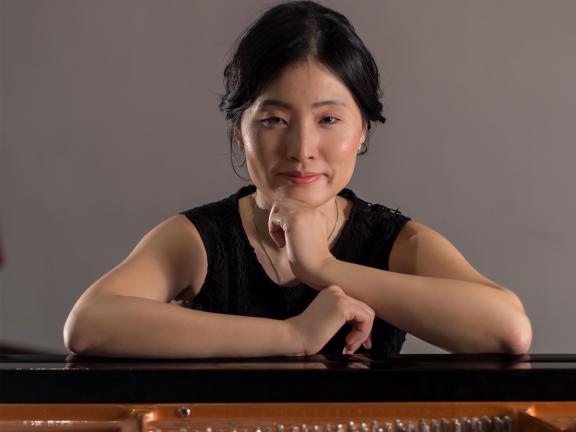 A women from the shoulders up extends her arms forward and stares directly forward.