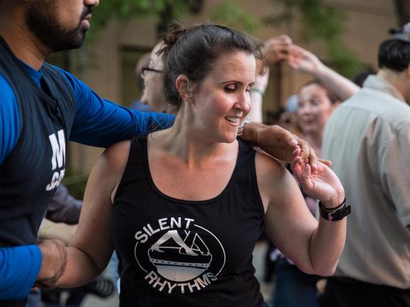A woman wearing a shirt that says "Silent Rhythms" dances with a male partner, who has his arm around her shoulders