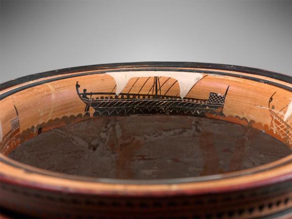  Inside the rim are four ships of war, with oars and sails.