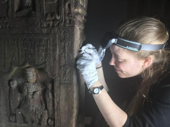 Conservator using a scalpel to take a sample from a crevice in a stone slab