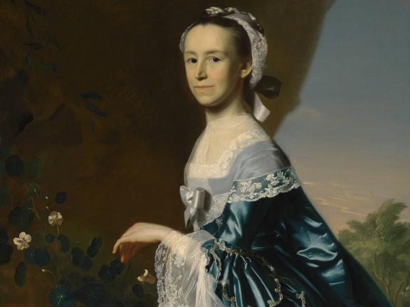A woman in an ornate blue dress stares straight forward in front of a pastoral landscape.