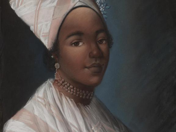 A woman in a pink and white shawl smiling.