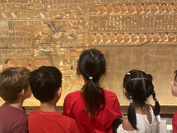 Young students from behind look at hieroglyphics in Egyptian gallery (SAC)