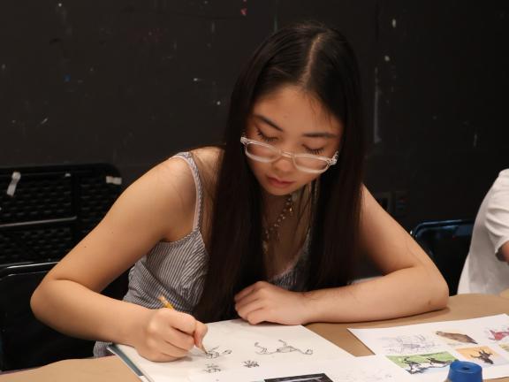 Female teen student draws in sketchbook in classroom (SAC)