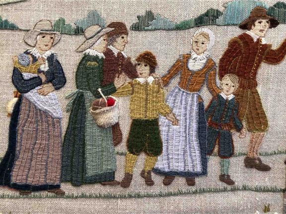 Embroidery of a colonial family scene with five adults and three children in period clothing