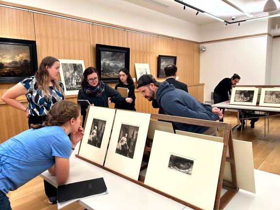 People look at art on display on a table.