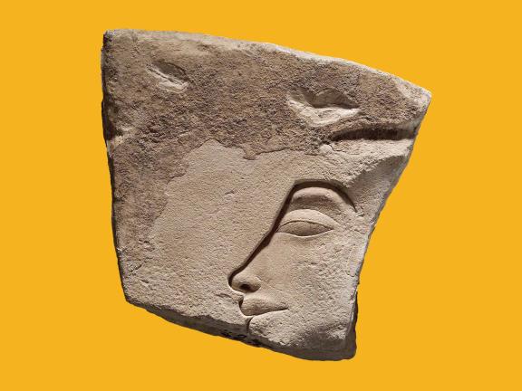 A weathered, uneven piece of limestone with a sunk relief profile of King Akhenaten's face