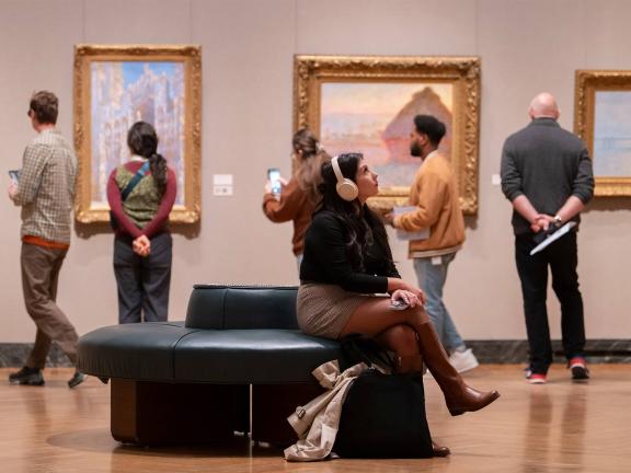 A visitor wearing head phones observes paintings in the Monet gallery