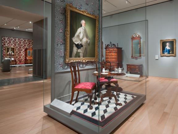 Display case with painting and chair and table set in Gallery 134