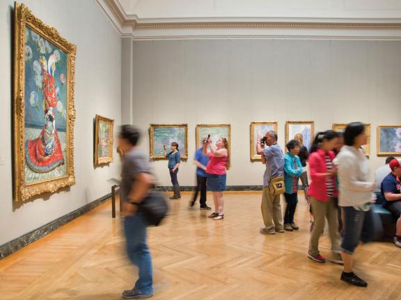 Visitors looking at French impressionist paintings in gallery