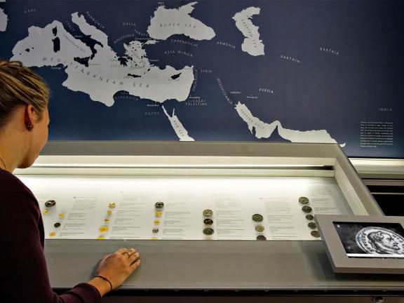 Visitor looking into display case of ancient coins