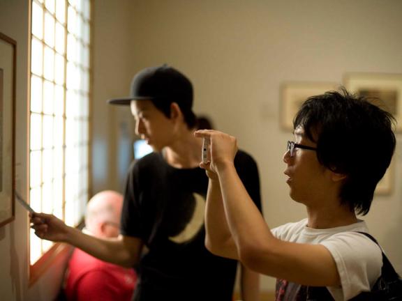 Visitor using smartphone to take photo of artwork on gallery wall