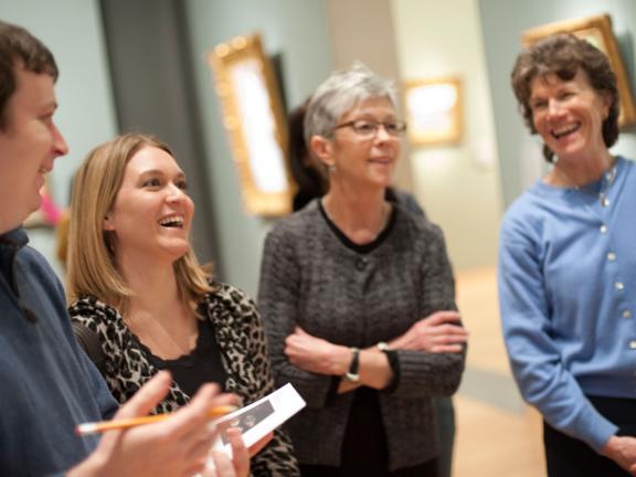 Four visitors looking at gallery wall, smiling