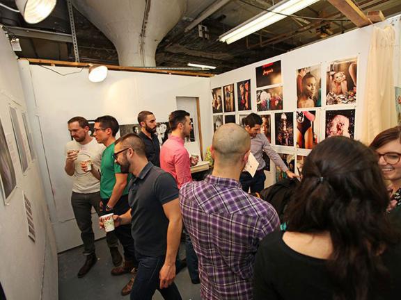 Visitors looking at artwork hanging on walls of SMFA graduate student studios