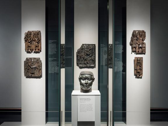 View of Benin gallery, with bronze plaques in background, bronze head in foreground