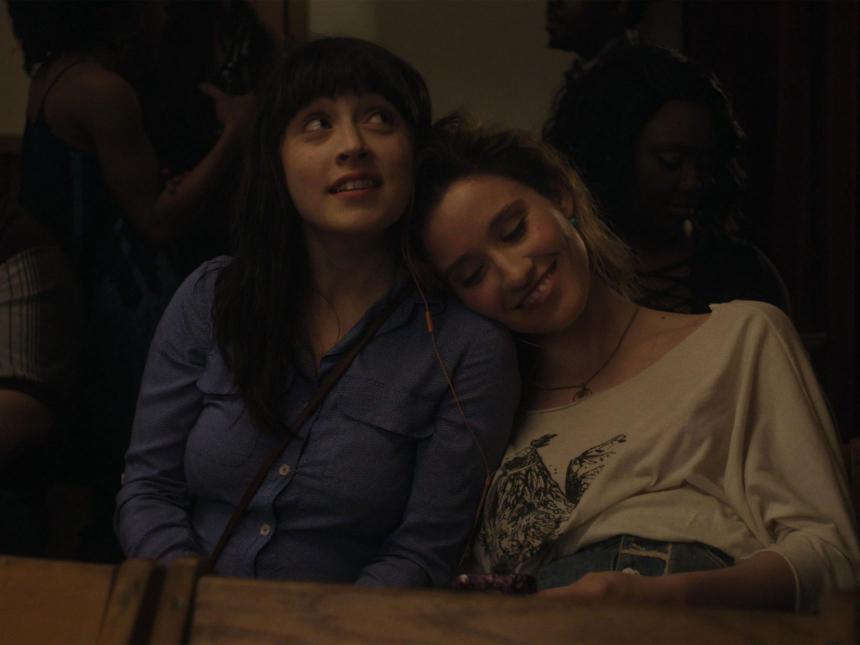 film still from Fourteen, depicting two women sitting next to each other, with one resting her on other's shoulder