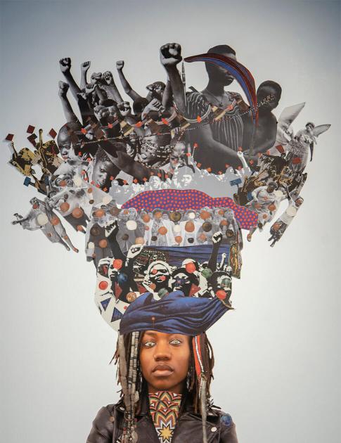 woman standing in front of a mixed-media collage depicting many raised fists