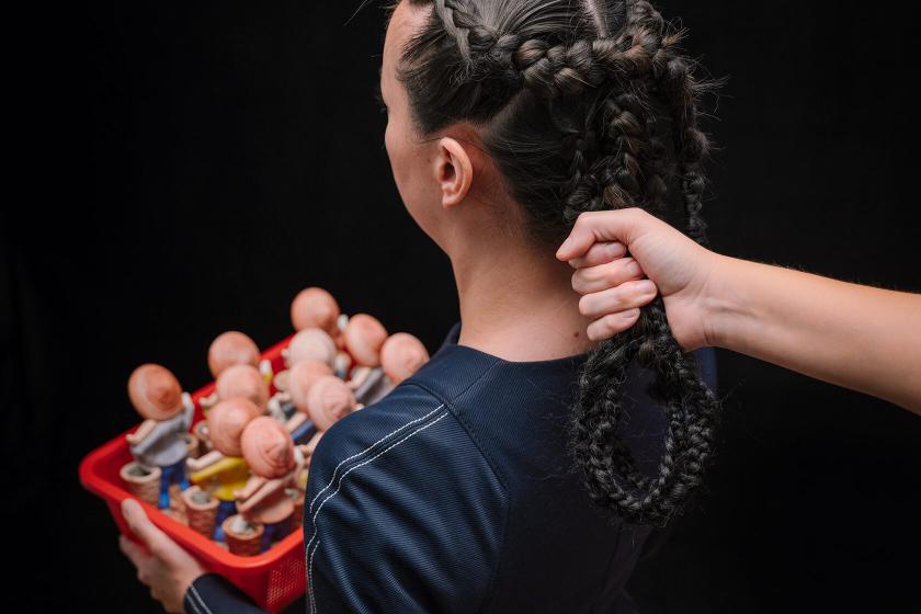 A hand tugs on a woman's braided hair.