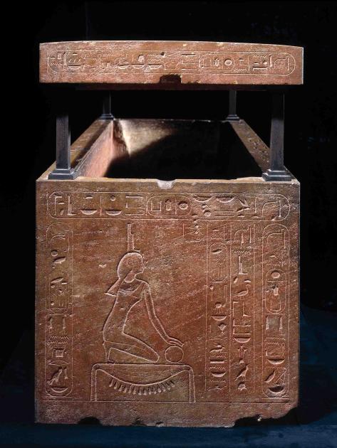 A stone box engraved with a stylized woman kneeling, surrounded by hieroglyphics.