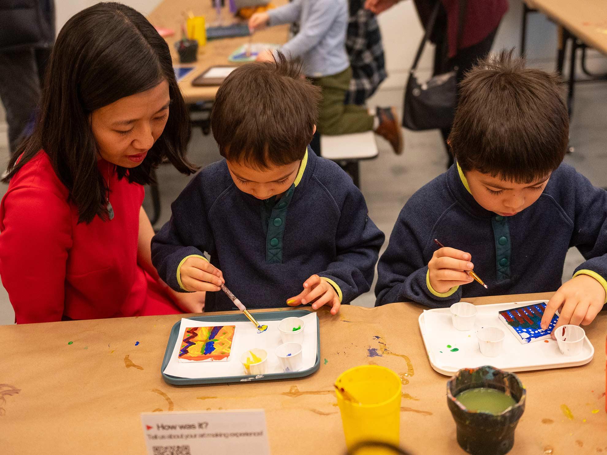 Mayor Wu sitting at table with two sons working on painting activity