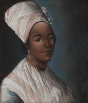 A woman in a pink and white shawl smiling.