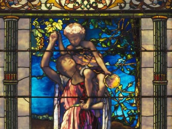 A stained glass window depicting a woman holding a young boy on her shoulder.